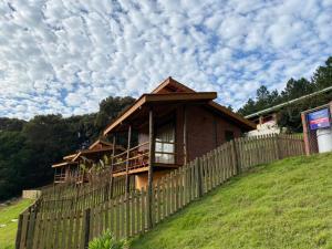 ein Haus auf einem Hügel mit einem Holzzaun in der Unterkunft Pousada Recanto Primavera in Piedade