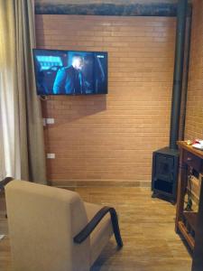 - un salon avec un canapé et une télévision murale dans l'établissement Pousada Recanto Primavera, à Piedade