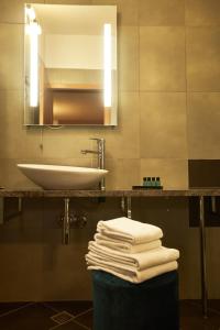 ein Badezimmer mit einem Waschbecken, einem Spiegel und Handtüchern in der Unterkunft Hotel Vila Emei in Maribor