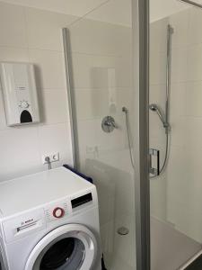 a washing machine in a bathroom with a shower at Ferienwohnung mit Waldblick in Leimen