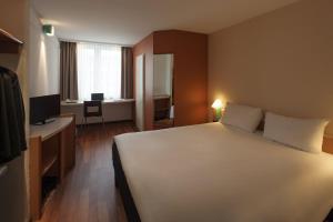 a bedroom with a large white bed and a desk at ibis Nürnberg Hauptbahnhof in Nuremberg