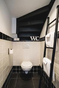 een badkamer met een toilet en zwarte en witte tegels bij Je B&B Giethoorn, incl fietsen! in Giethoorn
