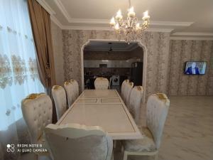 ein Esszimmer mit einem langen Tisch und weißen Stühlen in der Unterkunft Family villa in Qabala in Qəbələ