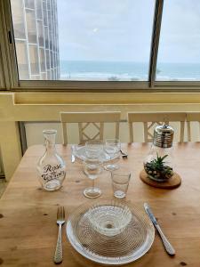 uma mesa de madeira com copos e utensílios em Superbe appartement face à la mer avec parking privatif em Canet-en-Roussillon