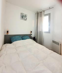 un grande letto bianco in una camera bianca con finestra di Superbe appartement face à la mer avec parking privatif a Canet-en-Roussillon Altre 26 foto