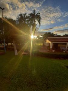 a sun shining through a palm tree in a yard at Associação Sabesp Cardoso - SP in Cardoso