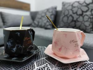 two coffee cups sitting on plates on a table at Apartmani Lukic Valjevo in Valjevo +2 photos