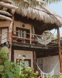 a house with a thatch roof and a balcony at Encantada Tulum in Tulum
