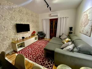 a living room with a couch and a flat screen tv at Apartamento Campos do Jordao Home Green Home in Campos do Jordão