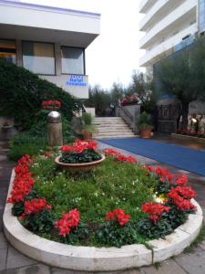 un jardín circular con flores rojas frente a un edificio en Hotel Promenade en Montesilvano