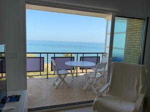 een kamer met een balkon met een tafel en stoelen bij Ático en primerísima linea de playa!!! in Denia