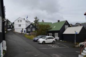 due auto parcheggiate in un parcheggio accanto alle case di Cosy house in the heart of Tórshavn (Á Reyni) a Tórshavn