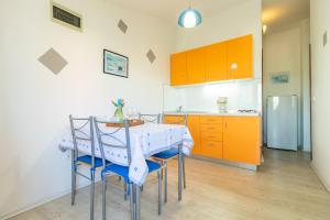 een keuken met een tafel en stoelen en oranje kasten bij Belvedere in Fažana