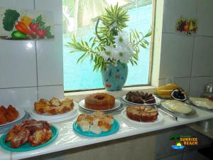 a table with different types of cakes and pastries at Pousada Sunrise Beach in Cumbuco
