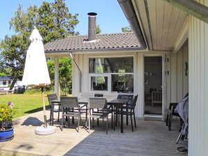 eine Terrasse mit einem Tisch, Stühlen und einem Sonnenschirm in der Unterkunft 10 person holiday home in Gr sted in Udsholt Sand