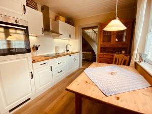 a kitchen with white cabinets and a wooden table at Hof Goosend - Urlaub an der Ostsee & Schlei in Gelting