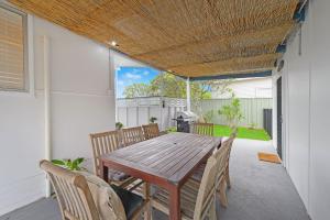 ein Holztisch und Stühle auf einer Terrasse in der Unterkunft Frangipani Cottage in North Haven