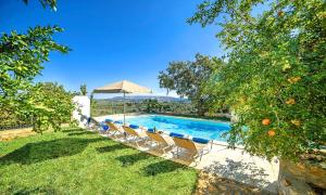 una piscina en un patio con sillas y sombrilla en Grand View Villa Private Heated Pool, en Georgioupoli