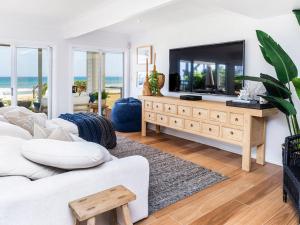 a living room with a white couch and a large tv at Absolute Beachfront Family Size Home in Gold Coast