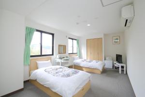 a hotel room with two beds and a window at Toya-onsen Hotel Hanabi in Lake Toya