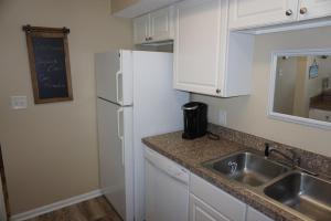a kitchen with a sink and a white refrigerator at Shores of Surfside I - 205 home in Myrtle Beach