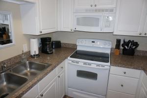 a kitchen with a white stove top oven next to a sink at Shores of Surfside I - 205 home in Myrtle Beach