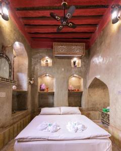 a bedroom with a bed with white sheets and a ceiling at Bait Al Aqr in Nizwa