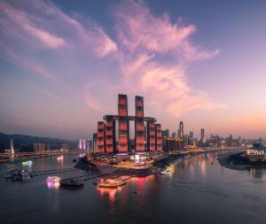 InterContinental Chongqing Raffles City, an IHG Hotel في تشونغتشينغ: مبنى كبير على نهر مع مدينة