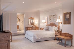Un dormitorio con una gran cama blanca y un televisor. en Hotel Manos Stephanie, en Bruselas