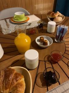 a wooden table with a breakfast of bread and orange juice at Hôtel la petite auberge in Arès