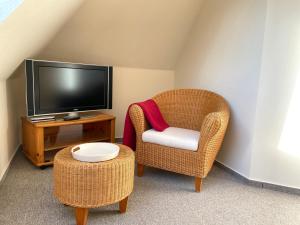 uma sala de estar com uma televisão, uma cadeira e uma mesa em Ferienwohnung Seeigel em Prerow