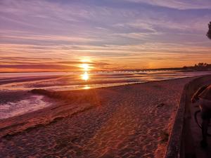 a sunset on a beach with the ocean at Hôtel la petite auberge in Arès