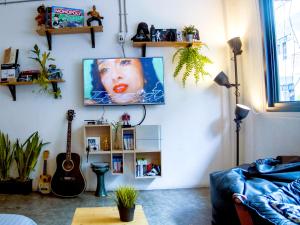 a living room with a tv hanging on a wall at HOLY SHEET Hostel in Bangkok
