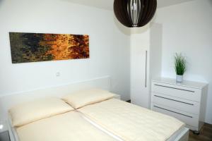 biała sypialnia z łóżkiem i komodą w obiekcie PENTHOUSE Griemann 1 mit Infrarotkabine und eigener Dachterrasse für max 4 Personen w mieście Illmitz