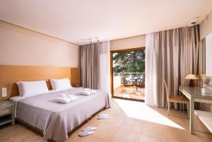 a hotel room with a bed and a large window at Olympion Sunset Halkidiki in Fourka