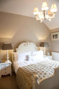 Un dormitorio con una gran cama blanca y una lámpara de araña. en The Salwey Arms, en Ludlow