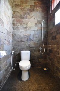 een badkamer met een toilet in een bakstenen muur bij Ana Warung & Bungalows in Gili Meno