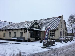 a building in the snow with a sign in front of it at Bij Hen op Ameland in Hollum