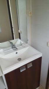 La salle de bains est pourvue d'un lavabo blanc et d'un miroir. dans l'établissement Camping La Dune Blanche - Daly's home, à Camiers