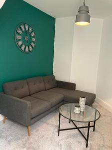 a living room with a couch and a clock on the wall at Ouse View Cottage in Goole