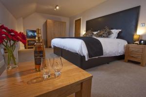 a bedroom with a bed with two wine glasses on a table at Kentraw Farmhouse Luxury Self Catering in Bruichladdich