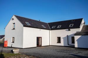 a white house with a black roof at Kentraw Farmhouse Luxury Self Catering in Bruichladdich +7 photos