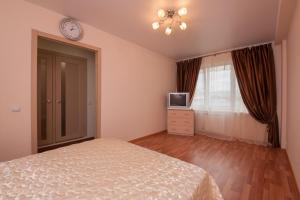 a bedroom with a bed and a clock on the wall at Kvartirov Apartments City in Krasnoyarsk