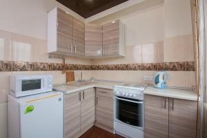 a small kitchen with white appliances and wooden cabinets at Kvartirov Apartments City in Krasnoyarsk