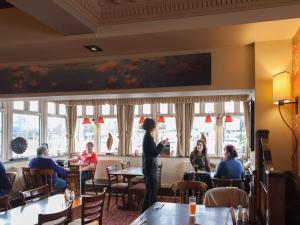 a woman standing in a restaurant talking to people at Kings Highway, Derby by Marston's Inns in Derby