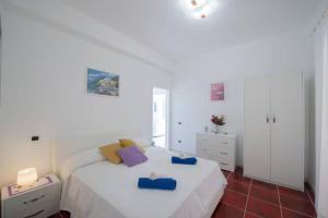 una camera da letto con un grande letto bianco con cuscini blu di Villa Brayan - Positano Magical Sea View a Positano
