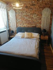 1 dormitorio con 1 cama grande y pared de ladrillo en Apartament Jeleń, en Złotów