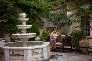 a woman sitting on a bench next to a fountain at Stone House Cave Hotel in Goreme