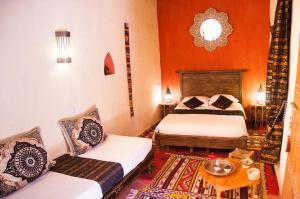 Zimmer mit 2 Betten und einem Tisch in der Unterkunft Dar Sofar in Agdz