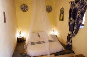 a bedroom with a bed with a mosquito net at Dar Sofar in Agdz
